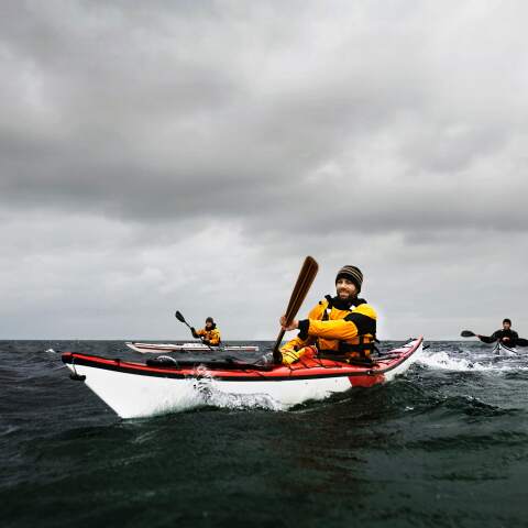 Hombre con chamarra en kayak en el mar